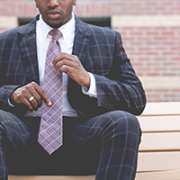 "man in a suit straightening his tie"