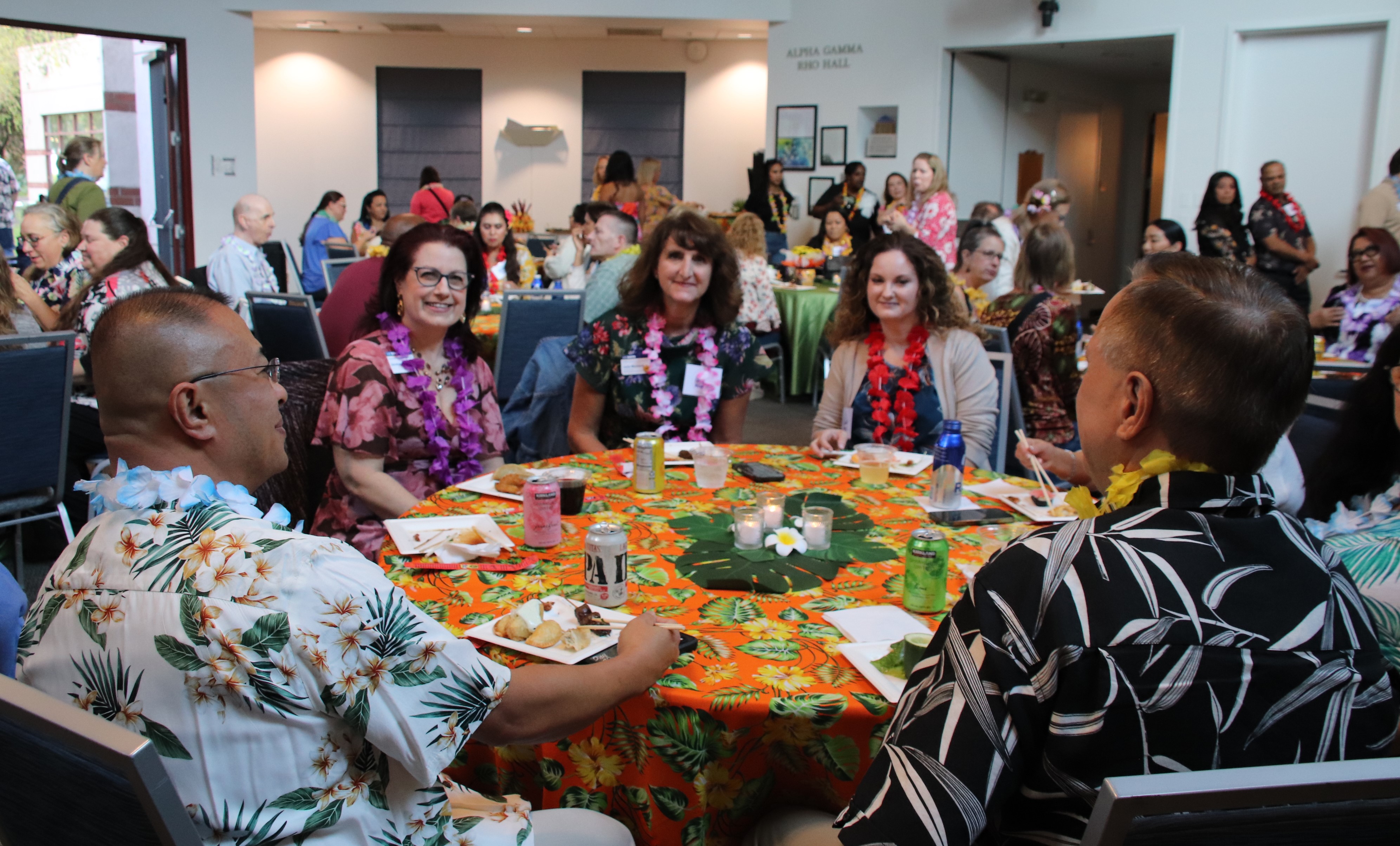 A group of people sitting at a round table smile at the camera.