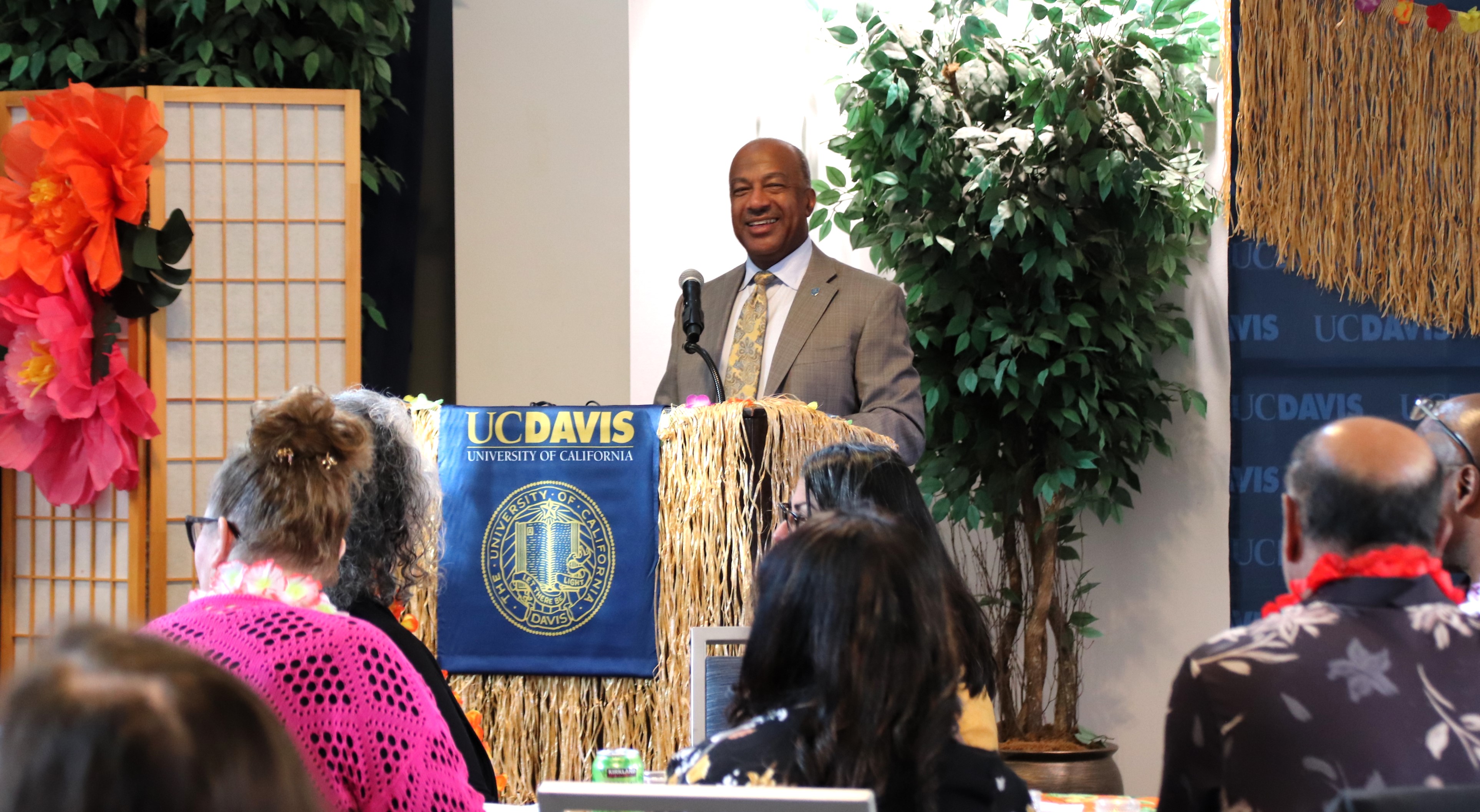 Chancellor Gary May smiles at a lecturn to a crowd of people.