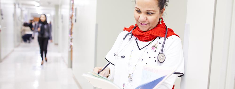 female doctor holding a folder of information she is reading in a hospital corridor