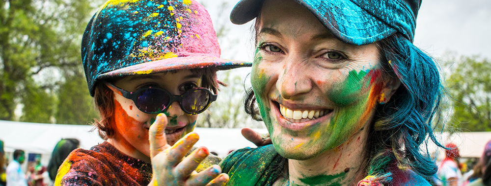 mother and son smiling and covered in colorful paint