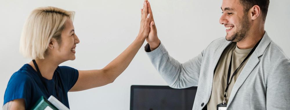 A man and woman highfive in the office.