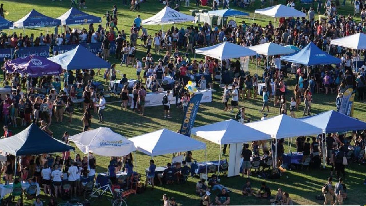 Aerial view of vendor pop-up tents on Hutchison Field at UC Davis, with people visiting each tent.