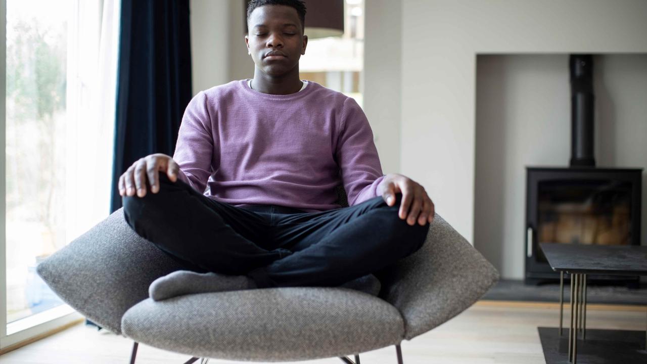 Man is sitting in a chair meditating.