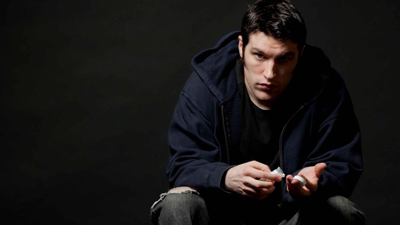 A man is sitting in a chair with his head down, staring off into the distance.