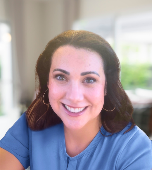 Smiling woman in blue top with hoop earrings, indoor portrait photo, blurred background