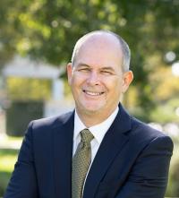 Jim Hankins Headshot. He is wearing a blue suit and smiling at the camera.