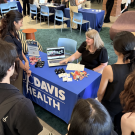 Students gathered around a Davis Health table at a busy campus fair