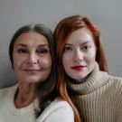 An older woman and a younger woman look at the camera with the sides of their faces touching.