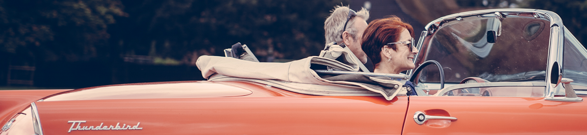 an older couple in a red convertible